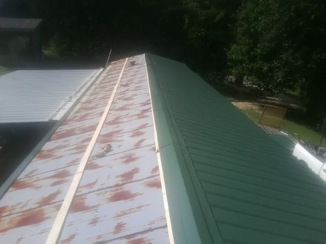 Old rusted panels beside newly installed green metal roofing — Wind Damage Roof Repair by Roofing Brothers in Gracemont