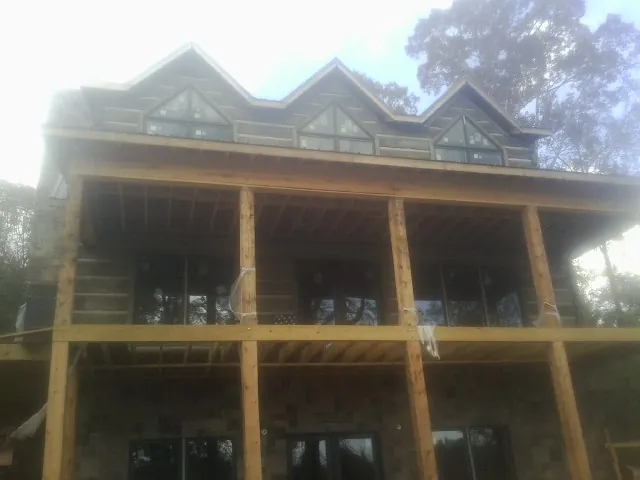 Dormers and porch framing on a large log home under construction — Roof Coating work by our crew in Gracemont