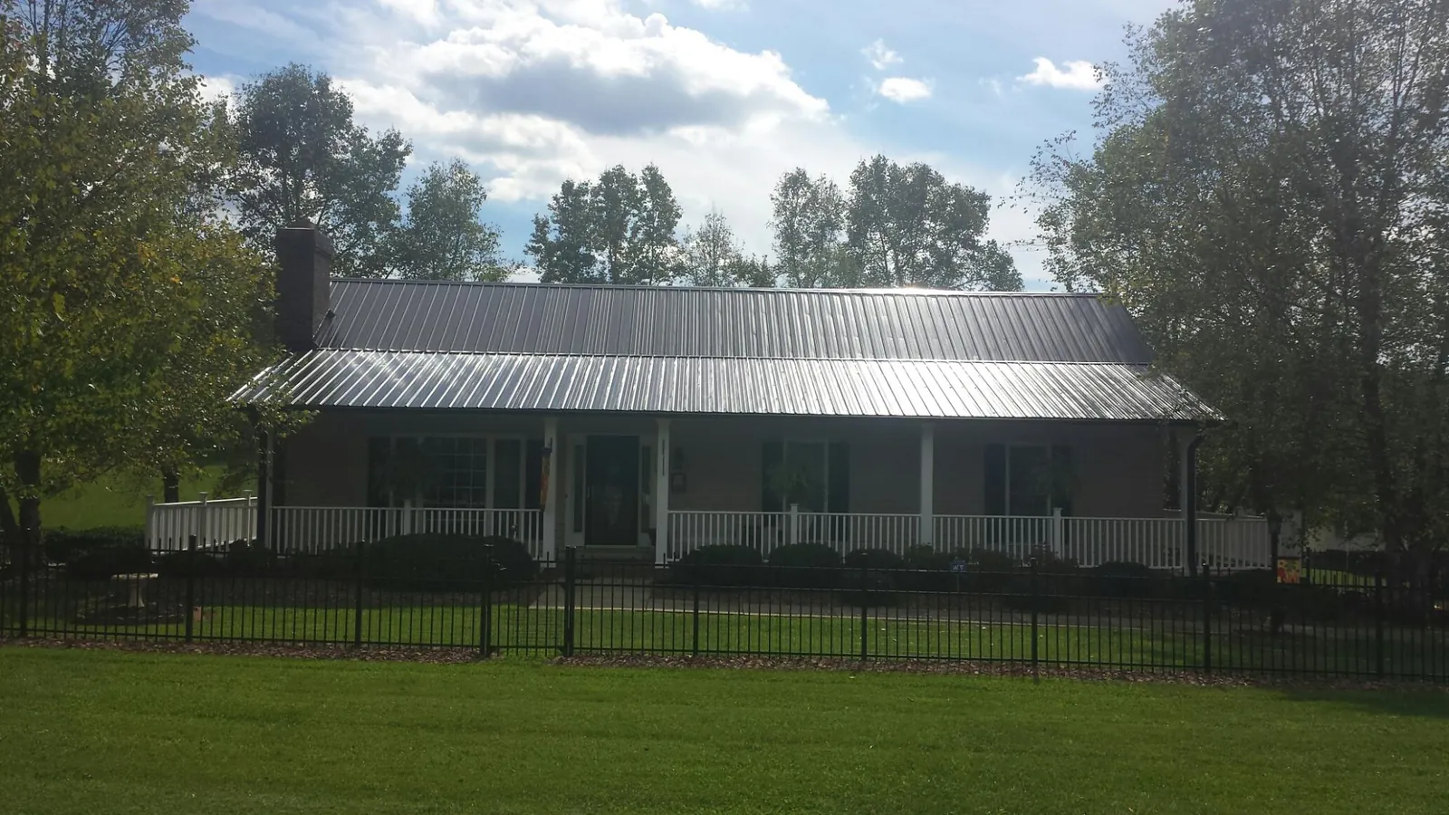 Gray metal roof on a brick ranch with a full width front porch — Gutter Guard Installation work by our crew in Gracemont