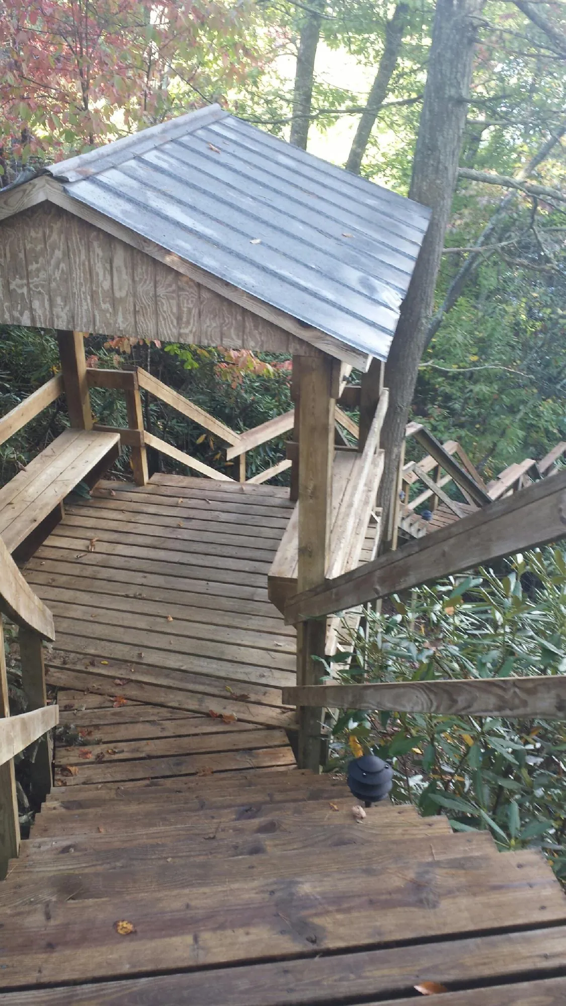 Metal roofed shelter over wooden steps on a wooded walkway — Skylight Repair & Installation work by our crew in Gracemont