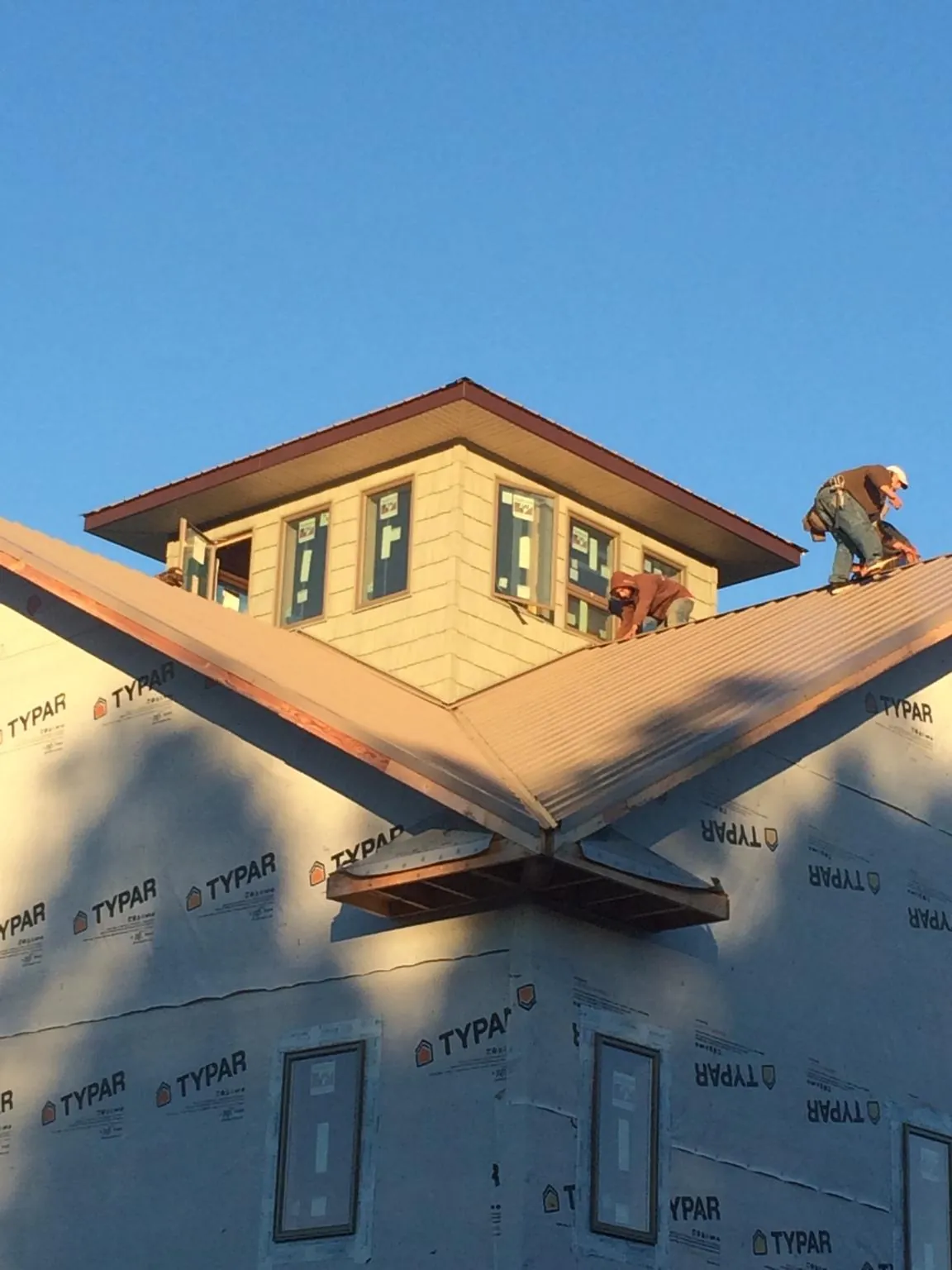 Roofers working around a rooftop cupola on a new metal roof at sunset — Roof Waterproofing in Gracemont by Roofing Brothers